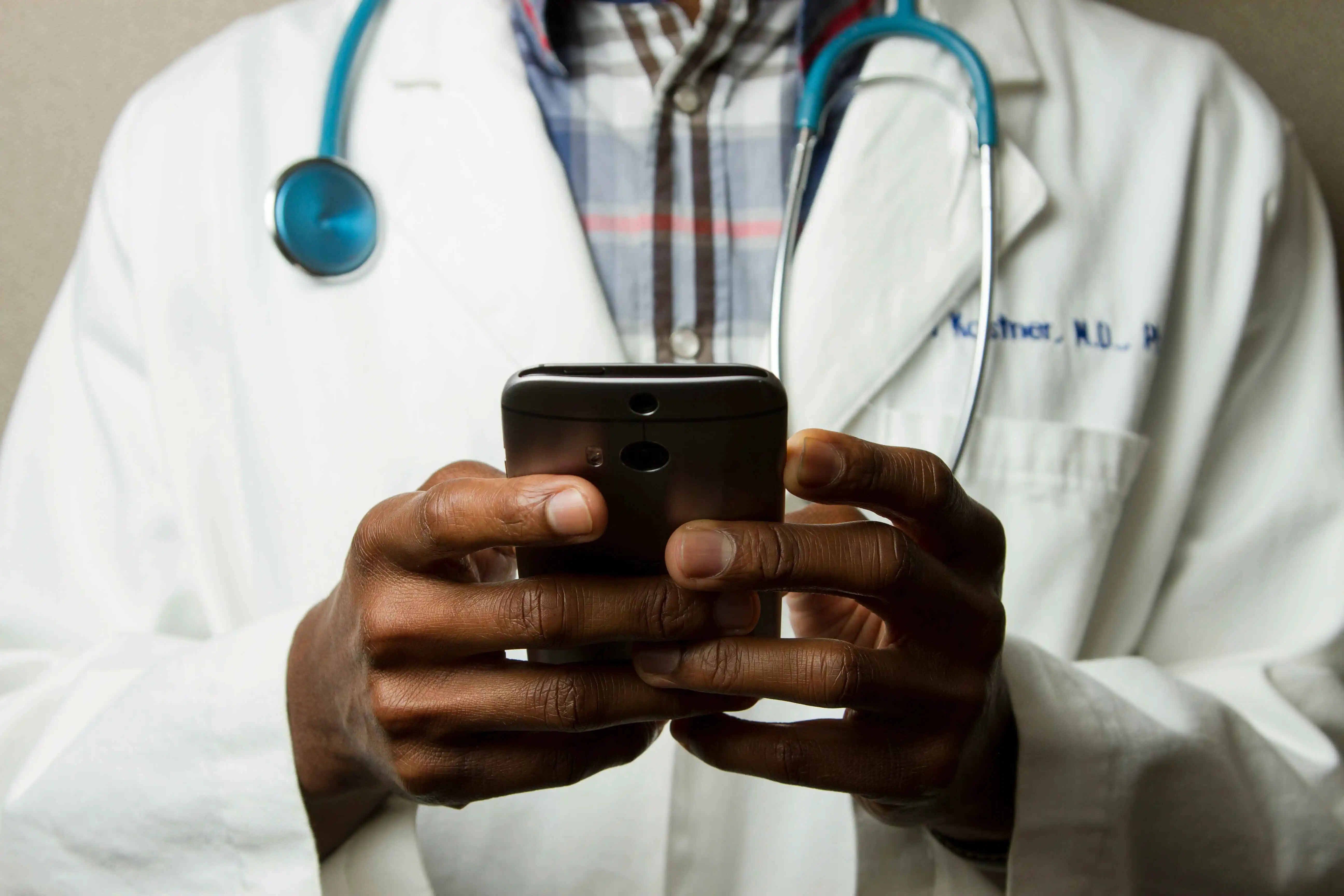 A medical doctor using a cell phone wearing a stethoscope bought at Iorstore Medical Instruments